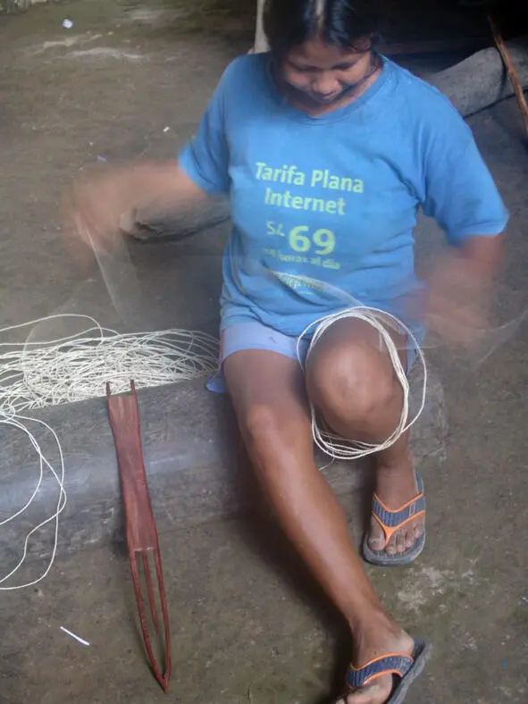 Женщина бора с деревянным челноком используемым для плетения гамака Нити - фото 28