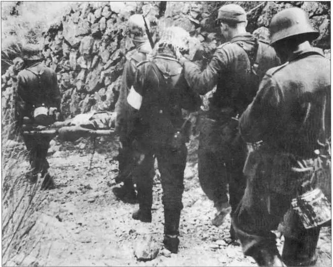 Немецкие солдаты несут раненого товарища вдоль каменной стены к месту - фото 214